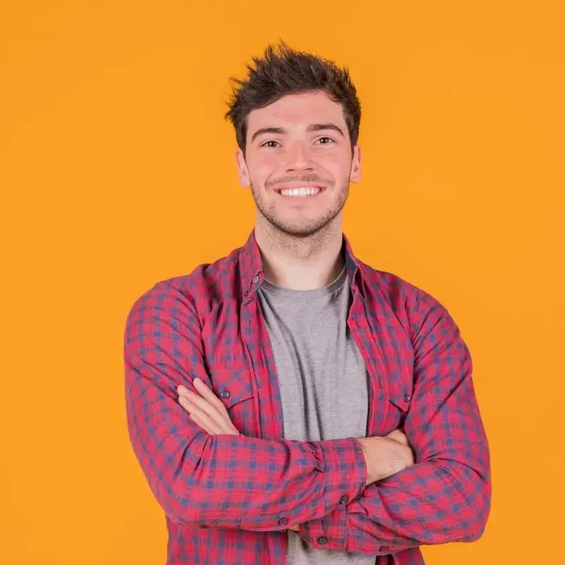 portrait-smiling-young-man-with-his-arm-crossed-standing-against-orange-backdrop